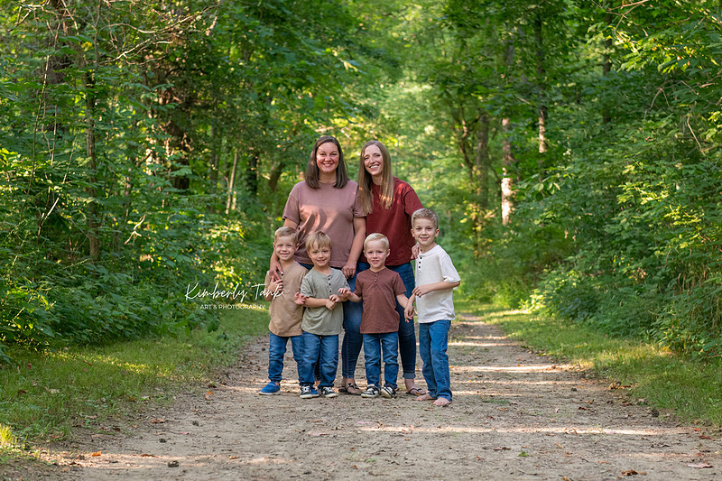 LGBTQ+ family with two moms and four young boys on a wooded path