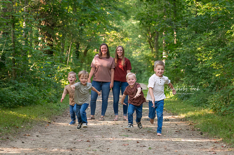 Triplets + big brother racing toward the camera during an outdoor family photo session with two moms