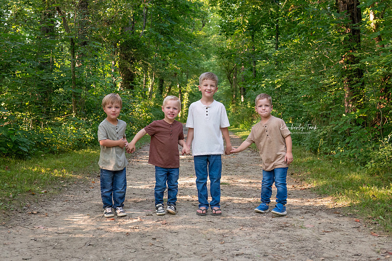 LGBTQ+ family with two moms and four young boys on a wooded path