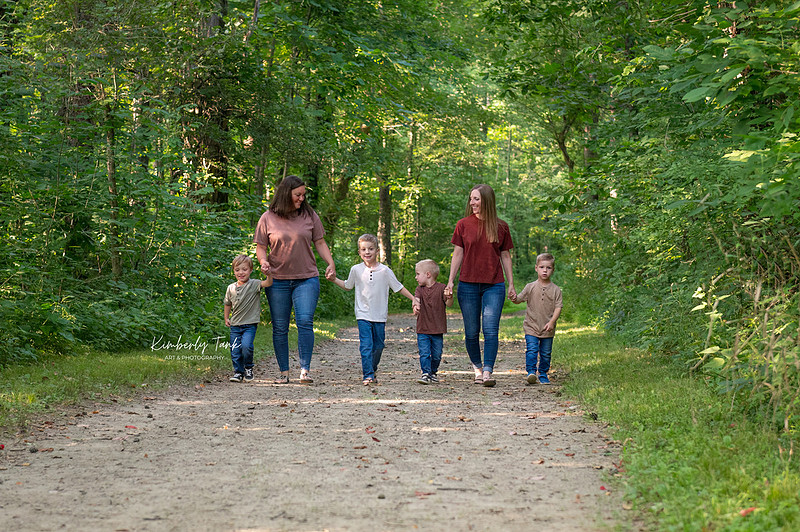 LGBTQ+ family with two moms and four young boys on a wooded path