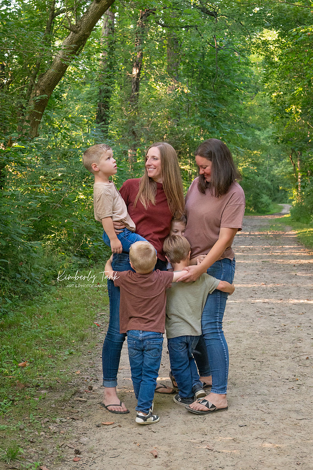 LGBTQ+ family with two moms and four young boys on a wooded path