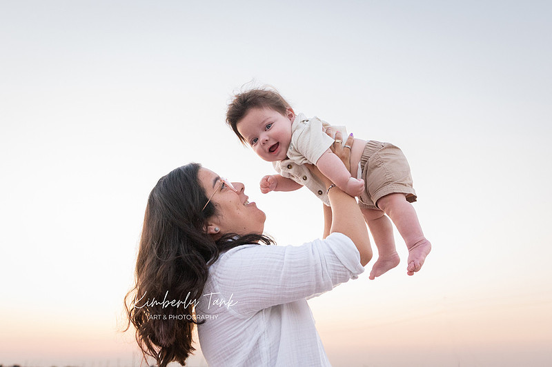 6 month old baby smiling big with mom at sunrise