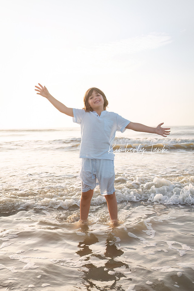 sunrise photos at the beach of boy standing in waves